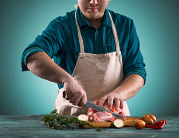 Butcher cutting pork meat on kitchen